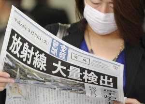 Žena čte noviny s titulkem: Naměřena radiace
